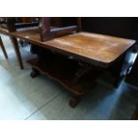 An early 20th century oak coffee table with carved end supports over shaped under tier