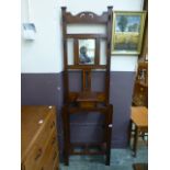 An early 20th century oak hall stand with beveled mirror over glove compartment and stick stand