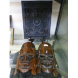 Two African carved wooden masks together with a carved plaque