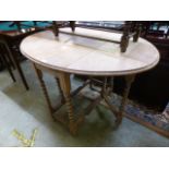 A stripped oak drop leaf table on barley twist legs