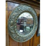An embossed brass framed circular mirror