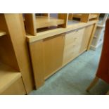 A modern sycamore sideboard having four centre drawers flanked by cupboard doors with a smoked