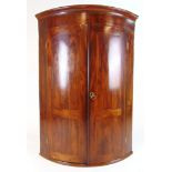 An 18th century mahogany and line inlaid bow front wall hanging corner cupboard,