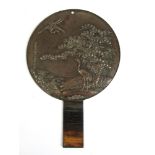 A 19th century Japanese bronze hand mirror having a cane wrapped handled,