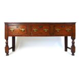 A late 17th century and later oak dresser base, the top over three drawers on turned front legs, h.