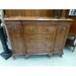 A walnut veneered breakfront sideboard having four drawers flanked by cupboard doors