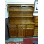 A modern pine dresser having plate rack to top the base having three drawers above three cupboard