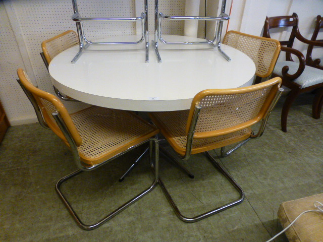 A white topped circular kitchen table on a five star chrome base along with a set of four caned