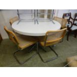 A white topped circular kitchen table on a five star chrome base along with a set of four caned