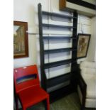 An ebonised open floor standing waterfall bookcase