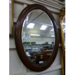 A mahogany oval framed bevel glass wall mirror