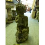 A composite stone garden ornament of seated child