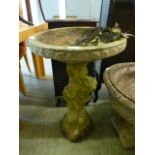 A stoneware bird bath with cherub design