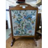 A mid 20th century oak framed fire screen having an embroidery under glass CONDITION