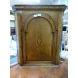 A reproduction oak wall mounted corner cabinet having an arch top single door