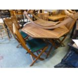 A teak folding garden table with a set of four matching folding chairs