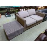 A modern plastic woven two seater garden settee together with a similar matching occasional table