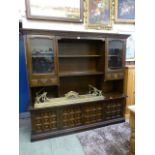 A Mexican style oak dresser having a raised top section of open storage flanked by glazed doors,