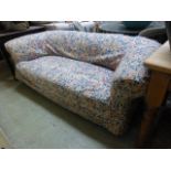 An Edwardian Chesterfield settee having a loose floral cover