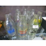 A collection of nine glass advertising milk bottles