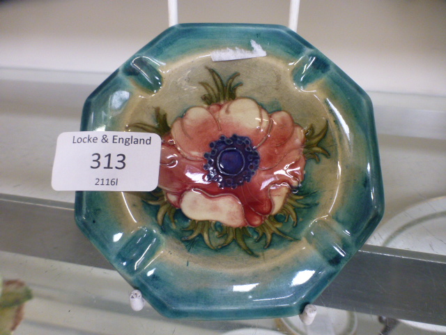 A Moorcroft ashtray decorated in the anemone pattern on a wood smoke ground