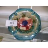 A Moorcroft ashtray decorated in the anemone pattern on a wood smoke ground