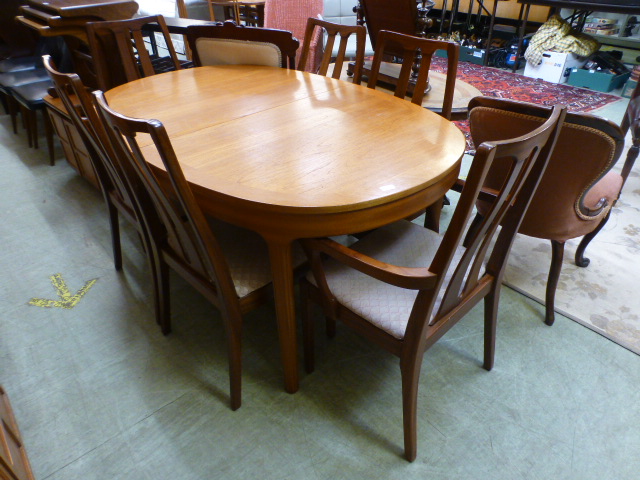 A mid-20th century teak extending dining table together with a set of four standard and two carver