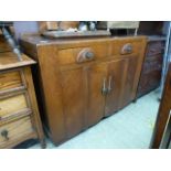 An early 20th century oak veneered sideboard having two drawers above cupboard doors