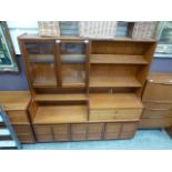 A mid-20th century teak cabinet having a part glazed top section with open storage,