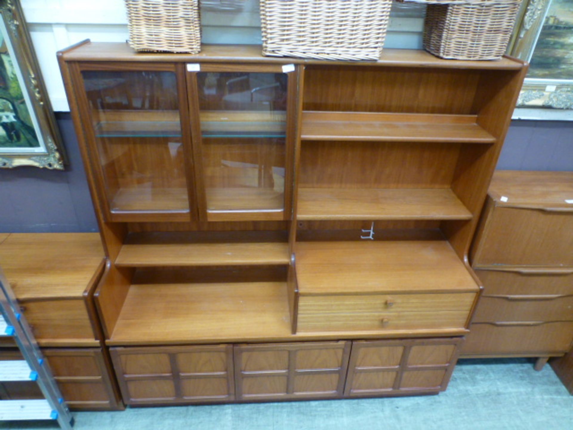 A mid-20th century teak cabinet having a part glazed top section with open storage,