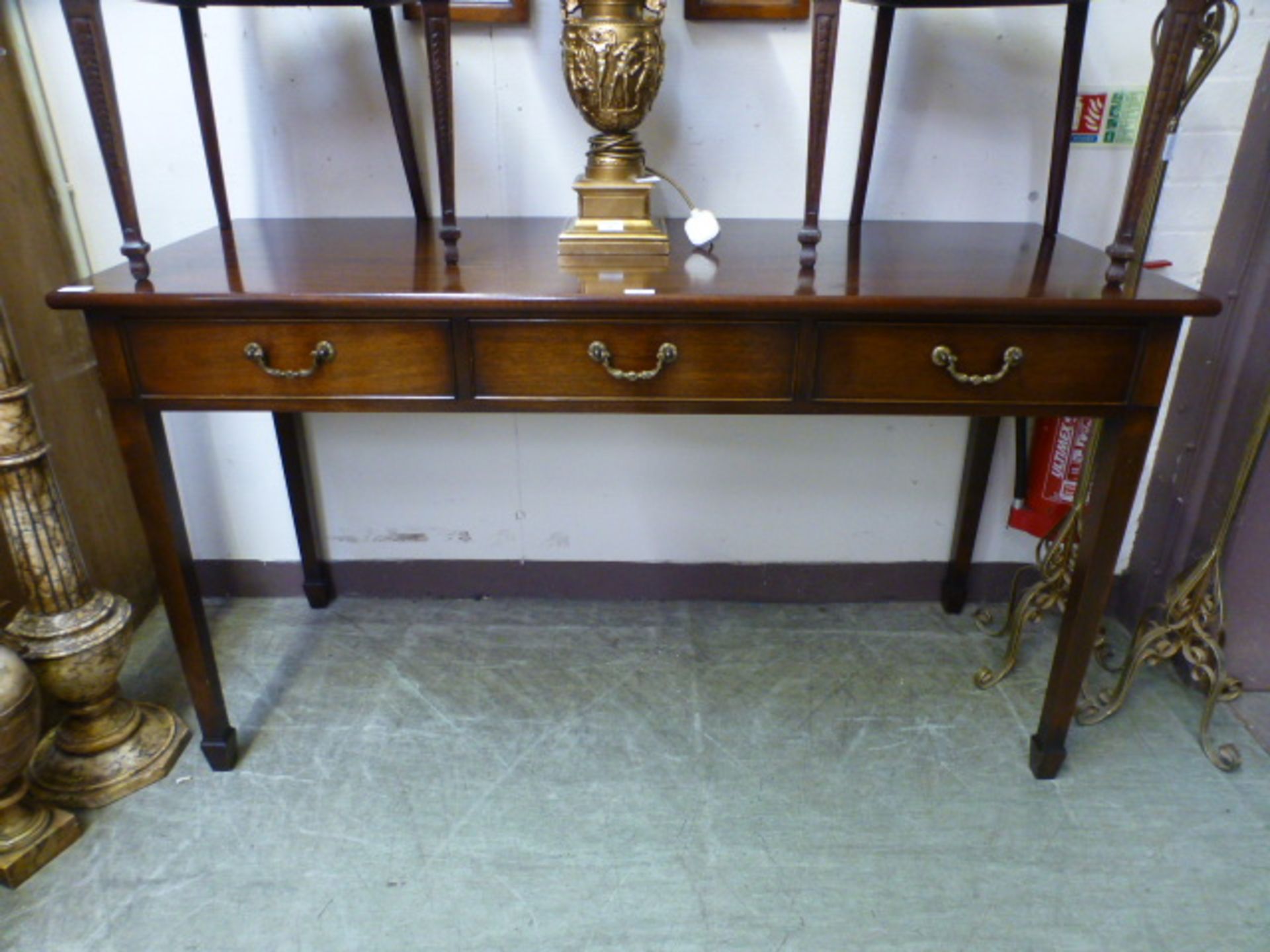 A reproduction mahogany three drawer serving table on square tapering supports