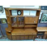 A mid-20th century teak unit having open storage above a pair of glazed doors and pull down front