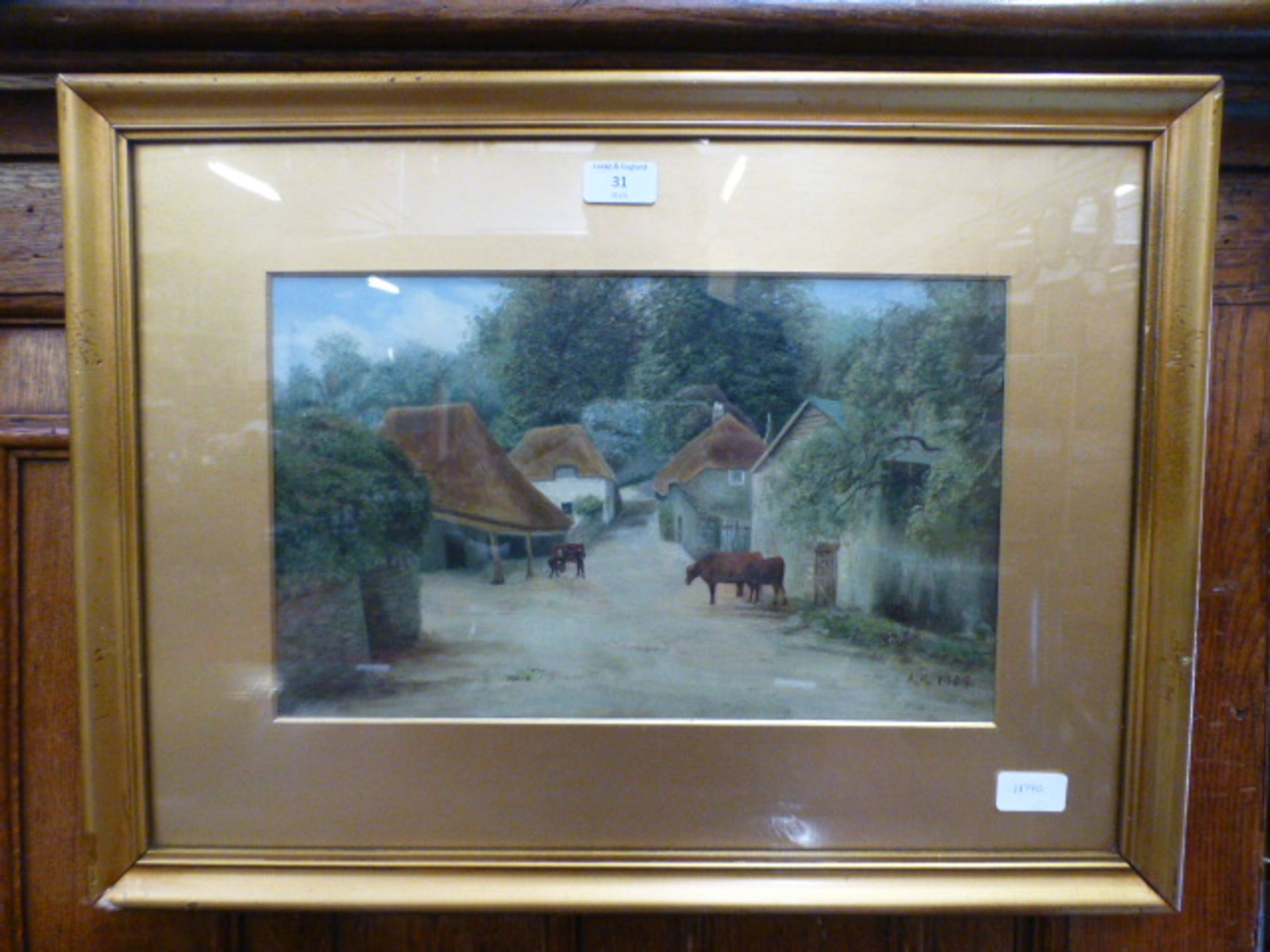 A gilt framed and glazed water colour of cattle in village scene signed bottom right A H 1909