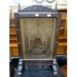 A 19th century oak fire screen having a distressed needlework to centre