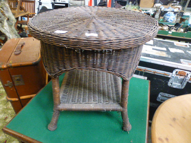 A circular topped wicker occasional table with under tier