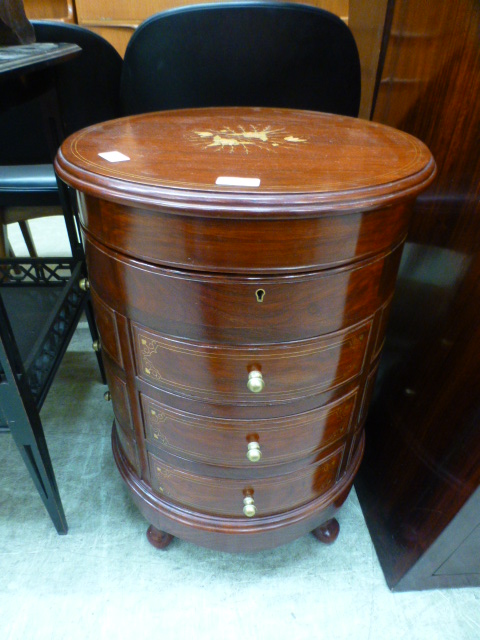 An oriental padouk circular cabinet having brass inlay with lift-up lid with multi drawers