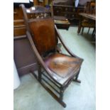 An Edwardian beech spindle back rocking chair having a embossed floral design to back and seat