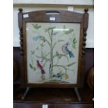 An oak framed fire screen having a needle work and a glass of birds in tree