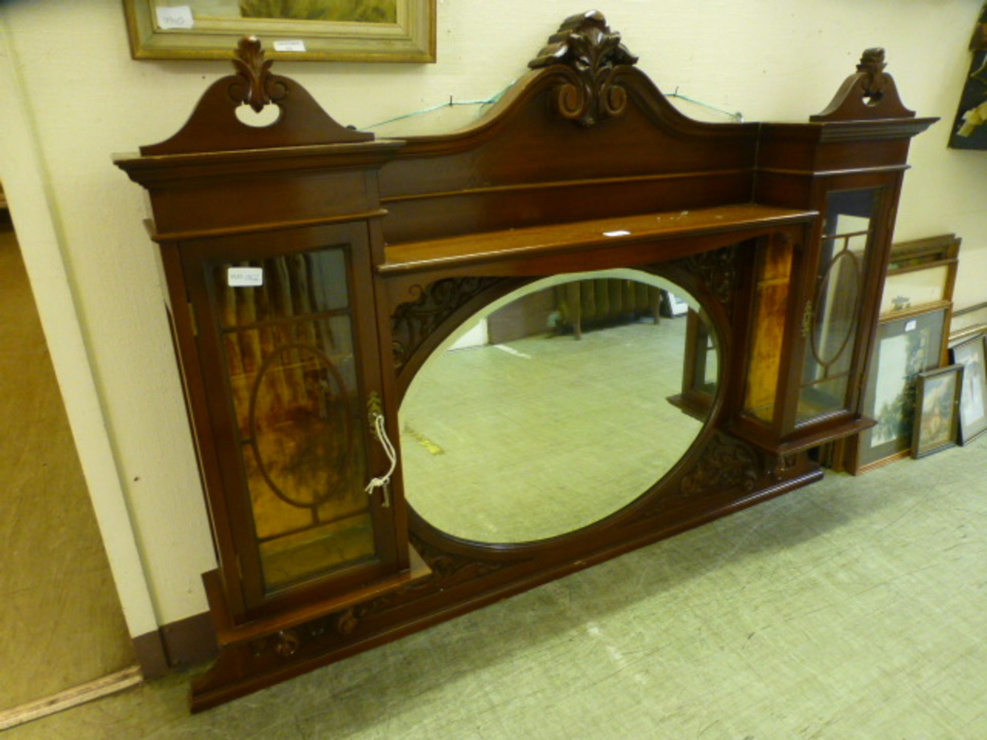 An early 20th century mahogany over mantle mirror having a bevelled glass centre mirror flanked by