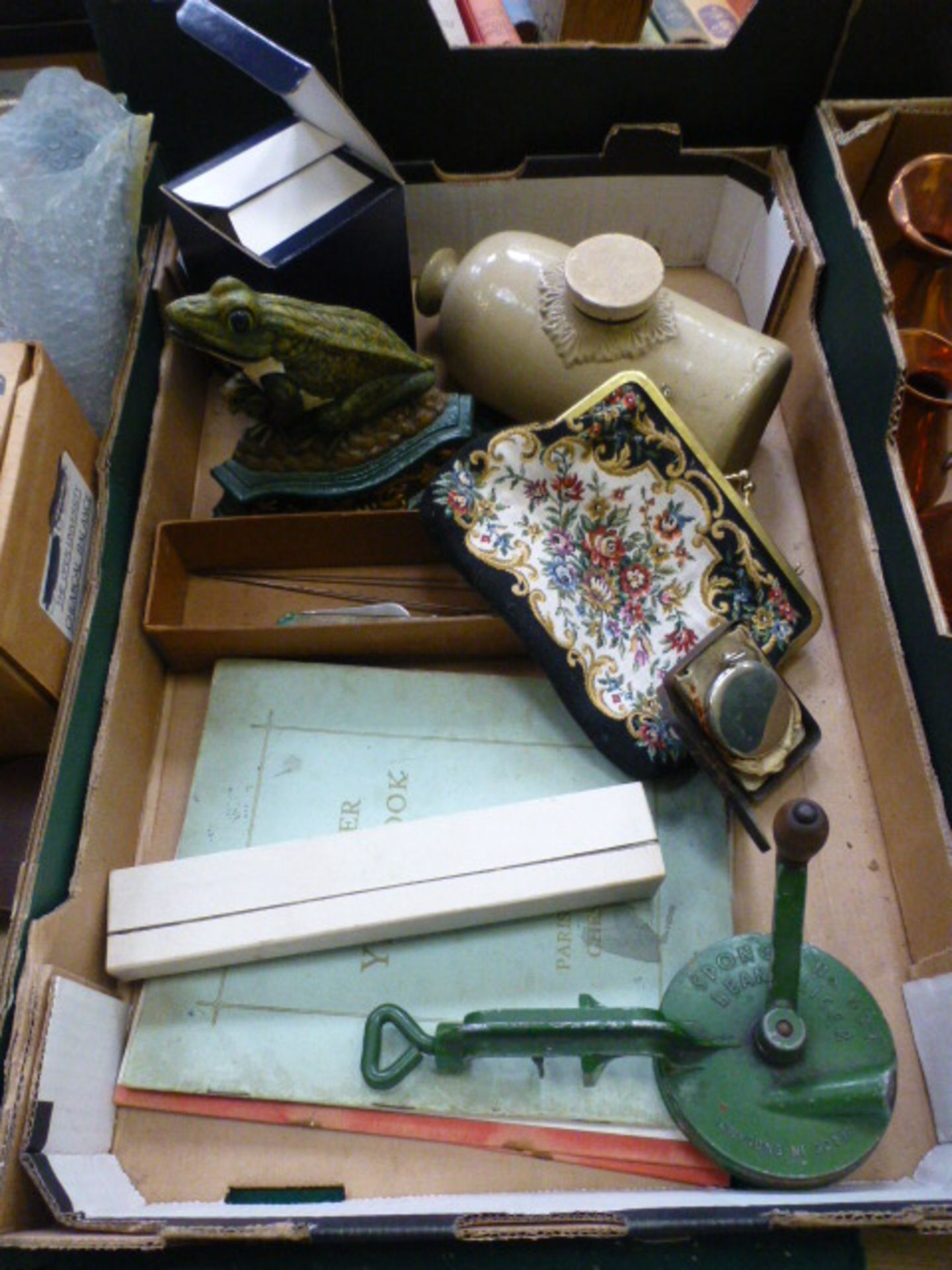 A tray containing a stoneware hot water bottle, fan, frog doorstop etc.