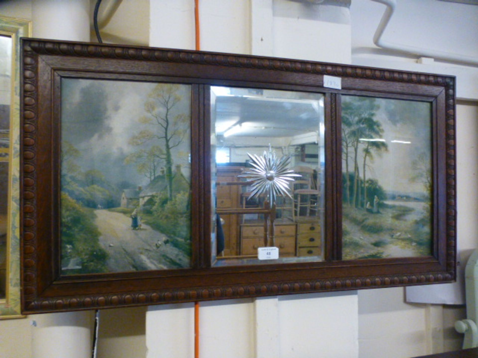 An early 20th century etched mirror flanked by prints of country scenes