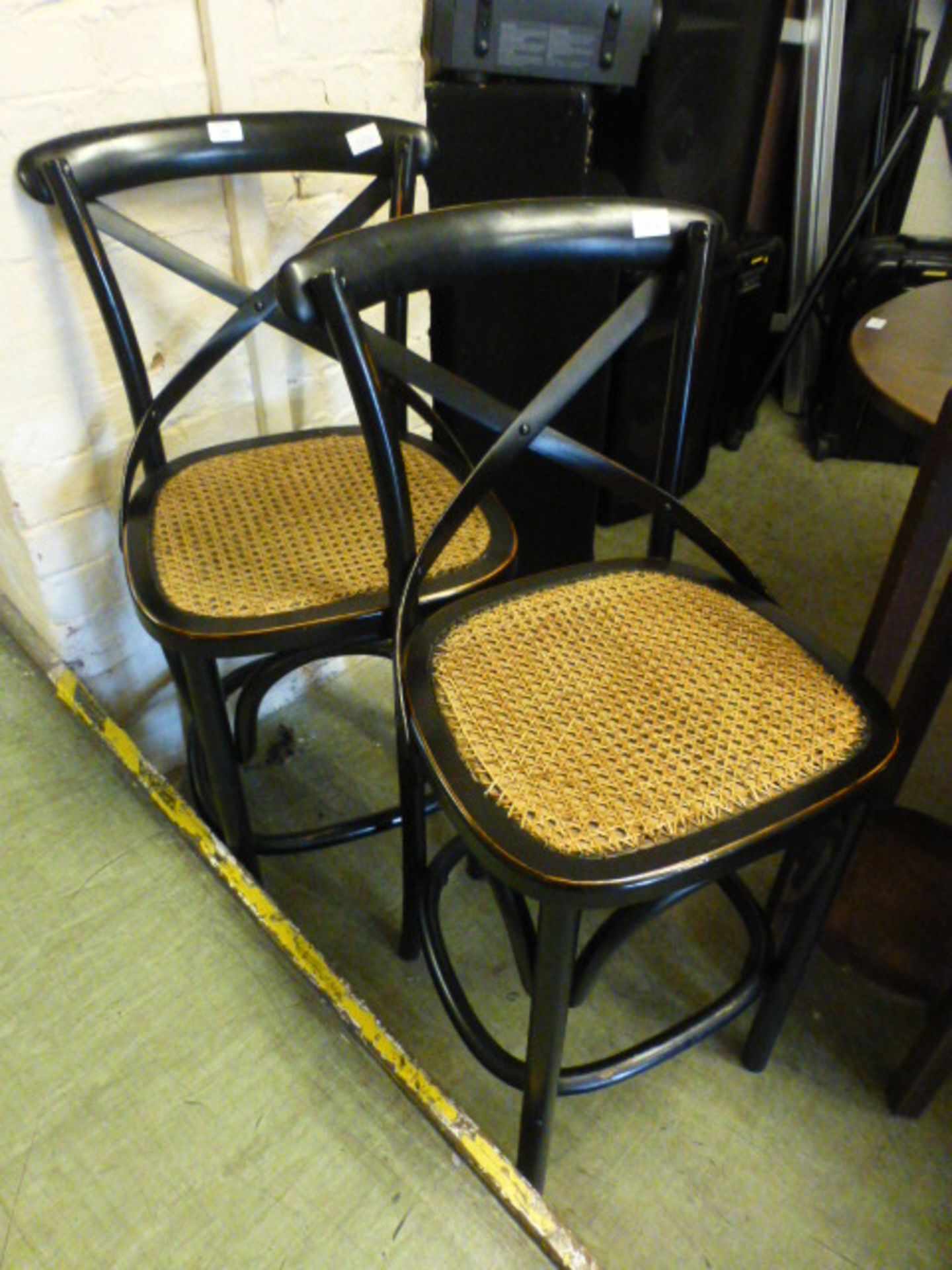 A pair of ebonised bentwood stools with cane seats