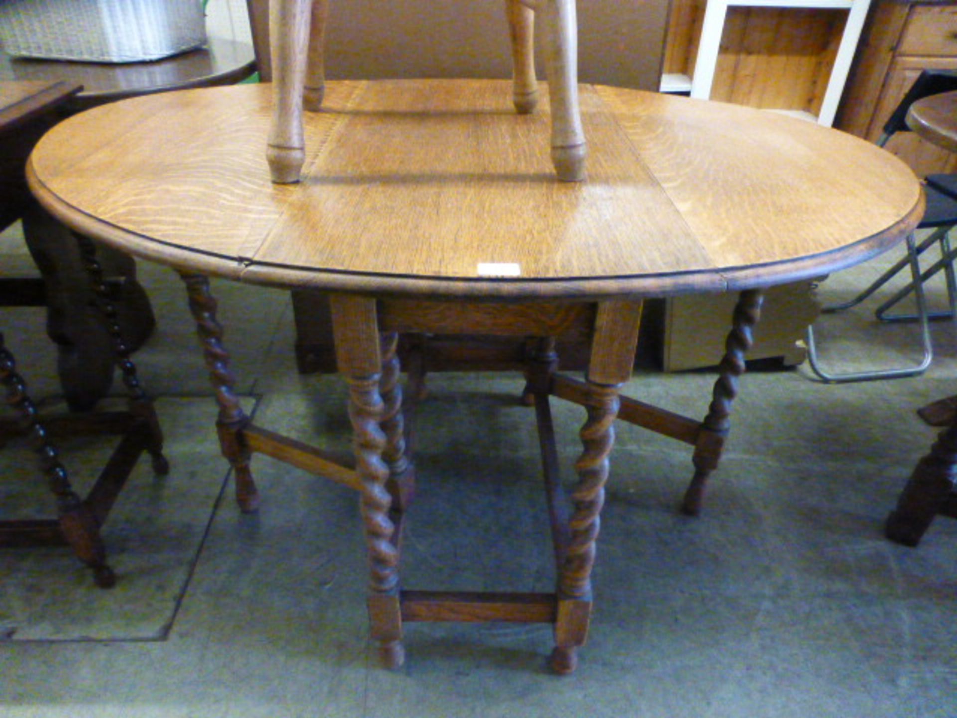 An early 20th century oak oval topped drop leaf table