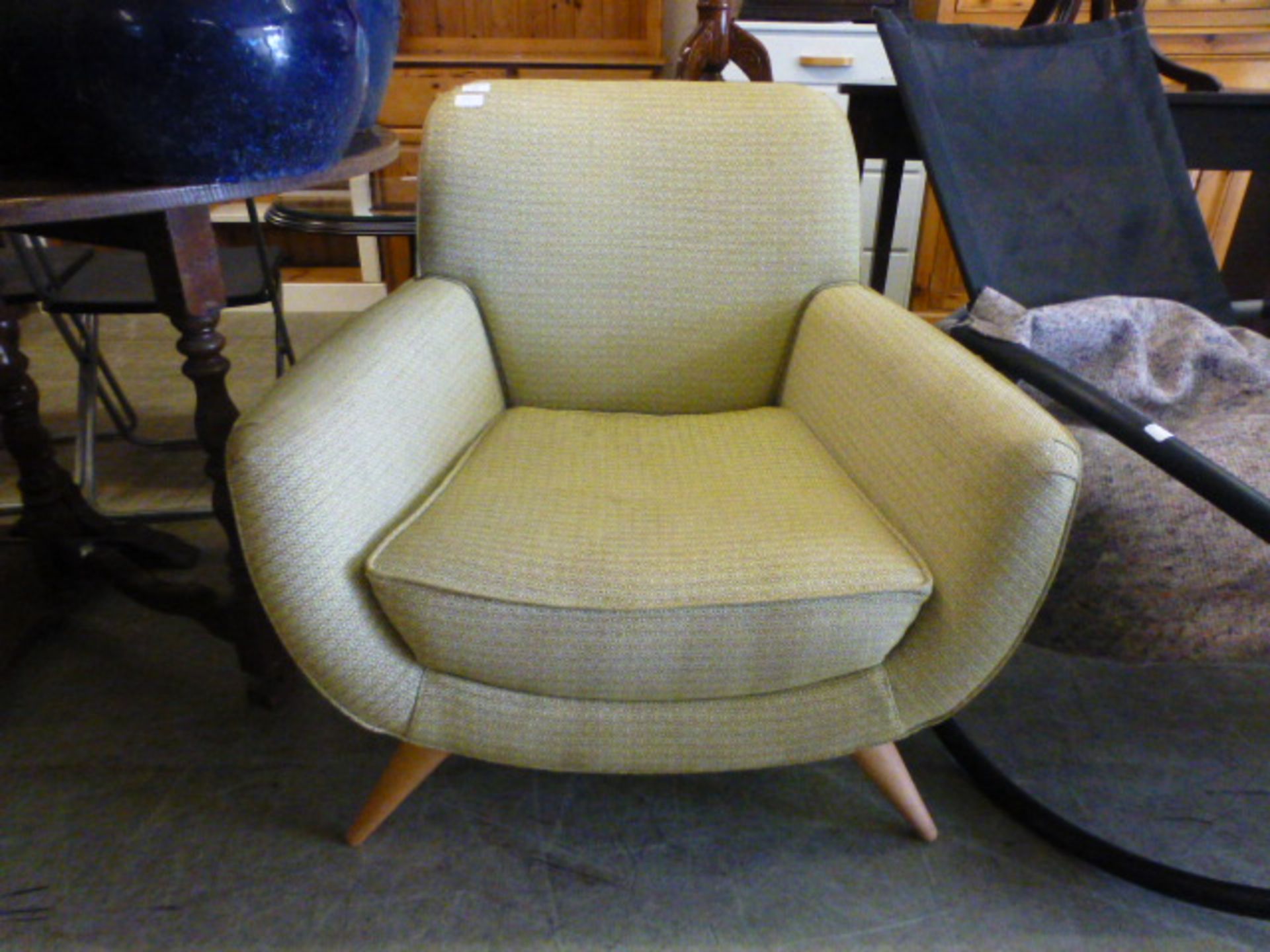 A modern armchair upholstered in an olive fabric on beech legs