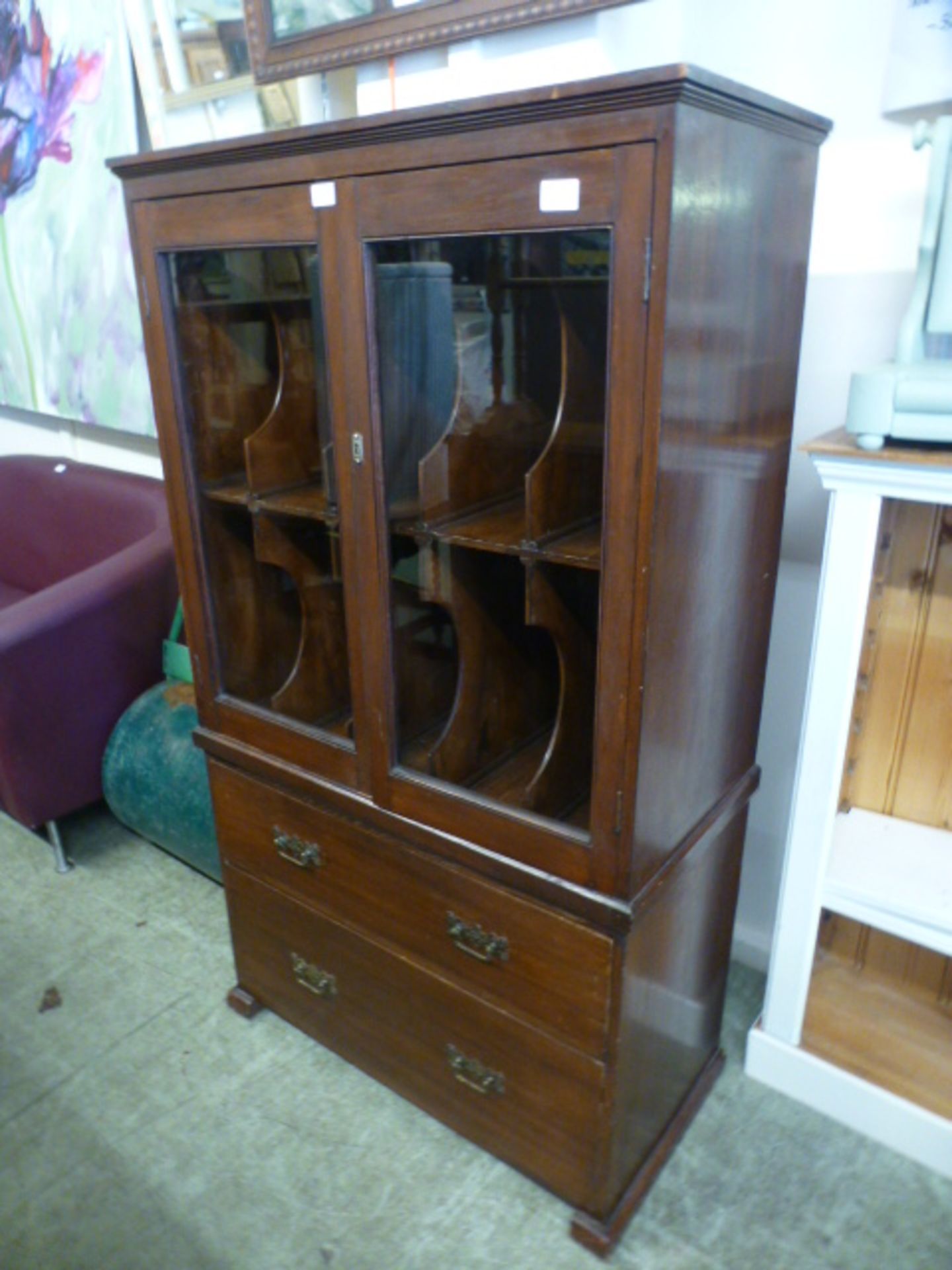 An early 20th century oak record cabinet with glazed doors enclosing fitted shelving over two