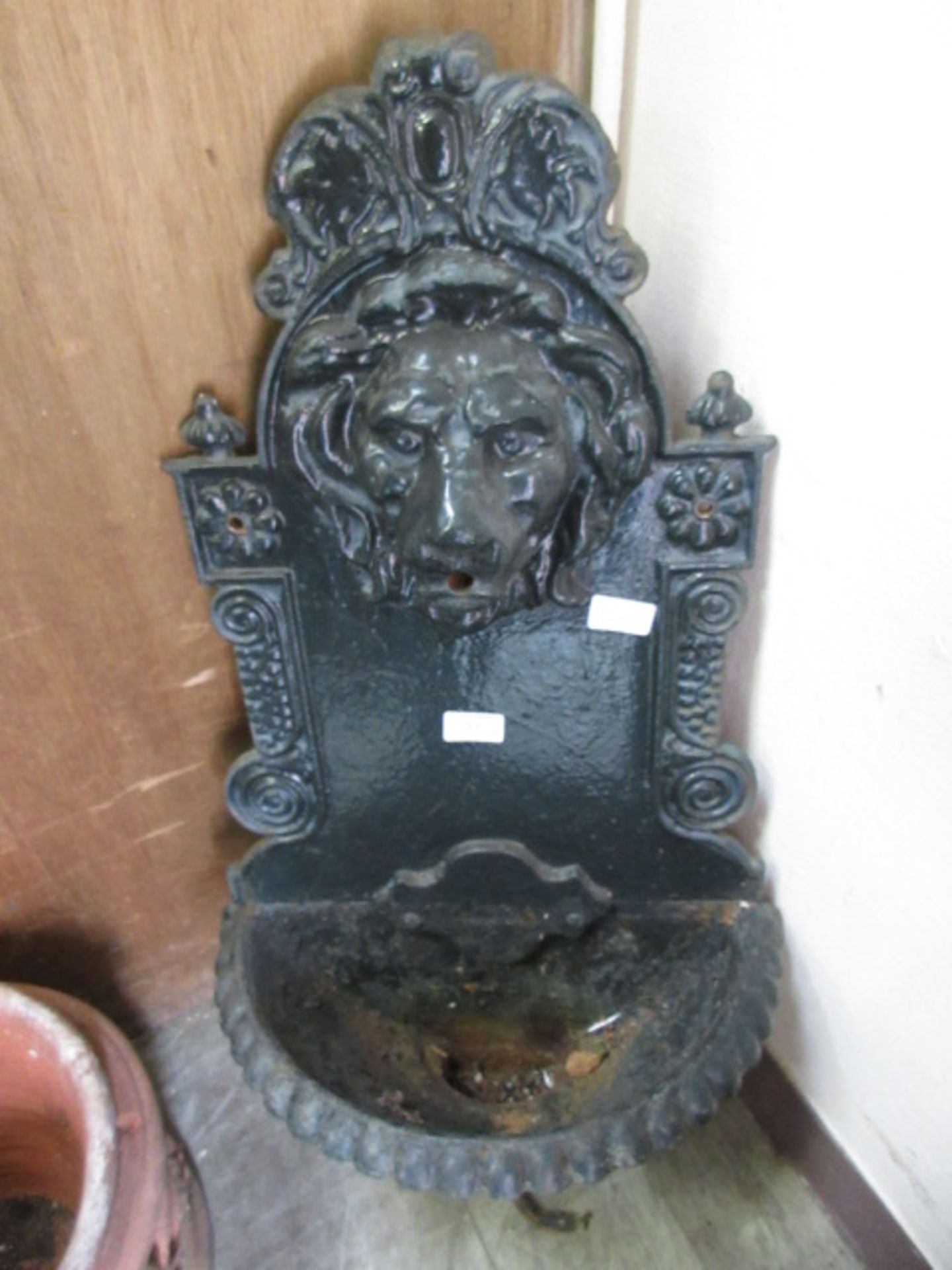 A cast iron garden fountain with lion mask spout
