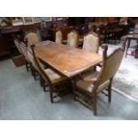 A reproduction refectory style table with a set six standard and two carver chairs having studded