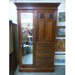 An Edwardian walnut compactum having a mirrored bevel glass door by four drawers