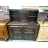 A mid-20th century oak court cupboard having a raised top section with cupboard door,