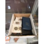 A box containing an assortment of coinage to include coin sets